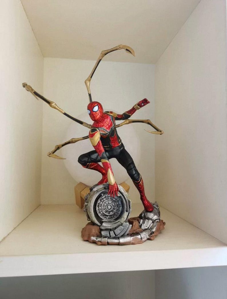 K&ouml;nnte beinhalten: Detaillierte Figur von Spider-Man in dynamischer Pose, mit rotem und goldenem Anzug und schwarzen Akzenten. Die Figur kniet auf einem detaillierten Sockel mit mechanischen Elementen und goldenen Spinnenarmen.