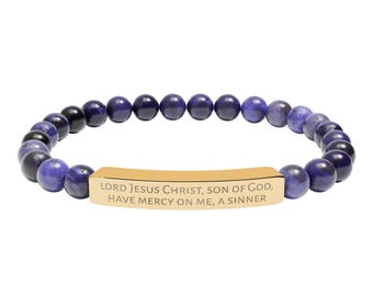 Peut inclure: Un bracelet de perles avec des perles sphériques bleu foncé et violettes. Une barre rectangulaire dorée au centre du bracelet porte l'inscription "LORD JESUS CHRIST, SON OF GOD, HAVE MERCY ON ME, A SINNER".