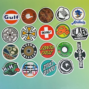 May include: A collection of colorful skateboard stickers with various logos and designs. The stickers feature brands like Santa Cruz, Independent, and Spitfire, with a mix of circular and rectangular shapes. The color palette includes red, blue, green, and orange.