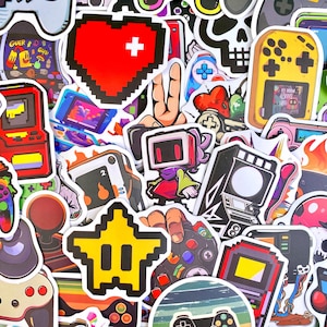 以下が含まれることがあります： ピクセルアートデザインのゲームをテーマにしたステッカーのコレクション。赤いハート、黄色い星、携帯ゲーム機、アーケード筐体、ゲームコントローラー、テレビ画面を頭にしたキャラクターなどが含まれています。