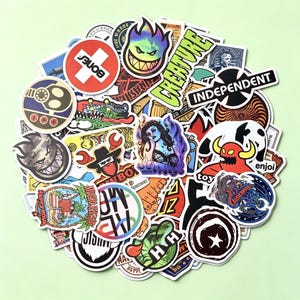 May include: A large collection of assorted vinyl stickers featuring various graphic designs, logos, and illustrations. The stickers include text such as Bones, Creature, Independent, Enjoi, and Happy Hour, displayed in a mix of vibrant colours and shapes.