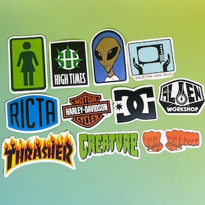 May include: A collection of colorful stickers with various designs. Includes a green and white sign with a stick figure, a black and green cannabis leaf, an alien, and a television with the text "exalt the new God". Other stickers feature the text "RICTA", "Harley-Davidson", "DC", "Alien Workshop", "Thrasher", "Creature", and "Toy Machine".
