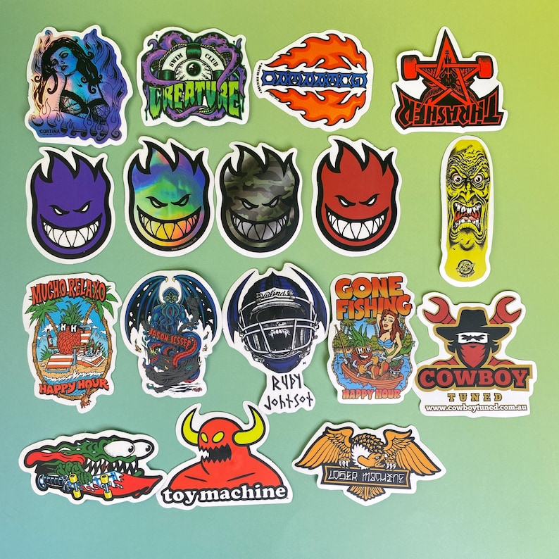 May include: A collection of colorful stickers with various designs. The stickers feature images of a woman, a creature, flames, a star, a skateboard, and a smiling face. Some stickers have text, including "THRASHER" and "COWBOY TUNED."