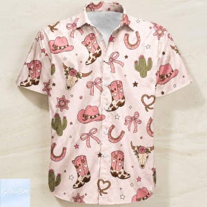 May include: A short-sleeved button-down shirt with a light pink background and a repeating pattern of cowboy boots, hats, cacti, horseshoes, bows, and stars. The shirt has a classic collar and a white inner lining.