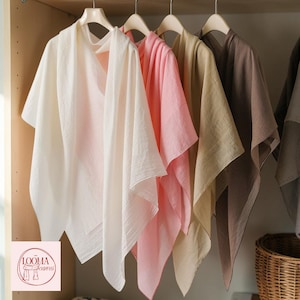 May include: A collection of lightweight, solid-coloured scarves hanging on wooden hangers. The scarves are displayed in a row, featuring shades of white, soft pink, beige, and brown. A logo with the text LOOMA Scarves is visible in the corner.