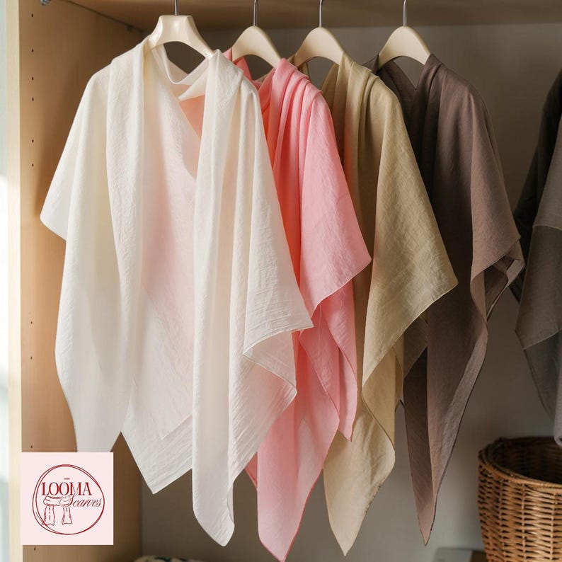 May include: A collection of lightweight, solid-coloured scarves hanging on wooden hangers. The scarves are displayed in a row, featuring shades of white, soft pink, beige, and brown. A logo with the text LOOMA Scarves is visible in the corner.
