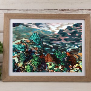 May include: A framed landscape painting depicting a mountain scene with a small house. The artwork features a palette of blues, greens, and browns, with a focus on the natural environment. The frame is a light brown color.