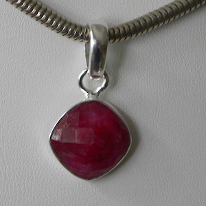 May include: A silver pendant necklace with a red gemstone. The gemstone is a square shape with rounded edges.