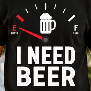 Puede incluir: Una camiseta negra de manga corta con un gráfico blanco de un indicador de combustible con un icono de jarra de cerveza. La aguja apunta hacia la E de vacío. Debajo del gráfico, el texto I NEED BEER aparece en letras mayúsculas blancas.