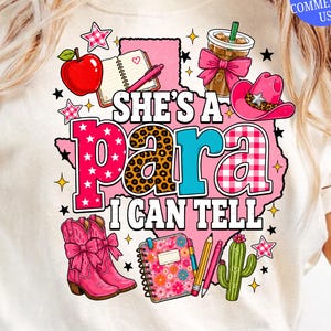 Può includere: Una t-shirt color crema con una grafica del contorno dello stato del Texas in rosa e il testo 'SHE'S A para I CAN TELL'. Il design include una mela rossa, un taccuino, una tazza di caffè, un cappello da cowboy rosa, stivali rosa e un cactus.