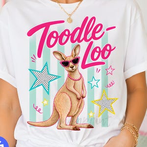 May include: White t-shirt with a kangaroo graphic wearing sunglasses and a necklace, with the text "Toodle-Loo" in pink. The design includes stars and a striped background in shades of blue and green.