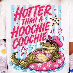 May include: White t-shirt with the text "HOTTER THAN A HOOCHIE COOCHIE" in pink. The graphic features an alligator wearing a pink hat and sunglasses, floating on a pink floral inner tube. Blue and pink stars and stripes complete the design.