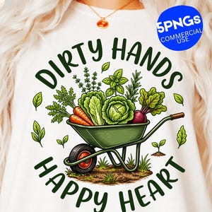 May include: White t-shirt with a garden-themed graphic. The design features a green wheelbarrow filled with vegetables, including carrots, lettuce, and beets. The text reads "Dirty Hands Happy Heart" in a circular arrangement.