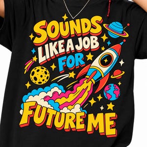 Könnte beinhalten: Ein schwarzes T-Shirt mit einer bunten Grafik und dem Text "SOUNDS LIKE A JOB FOR FUTURE ME". Das Design zeigt eine startende Rakete mit gelbem und rosa Abgasstrahl, einen gelben Mond, einen blauen Planeten mit Ringen und kleine gelbe Sterne.