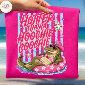 May include: Hot pink t-shirt with the text "Hotter Than a Hoochie Coochie" in pink and white. The graphic features an alligator wearing sunglasses, a pink cowboy hat, and a pink floral inner tube.