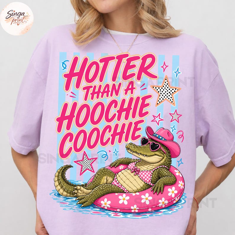 May include: A light purple t-shirt with the text "HOTTER THAN A HOOCHIE COOCHIE" in pink. The graphic features an alligator wearing sunglasses, a pink cowboy hat, and a swimsuit, floating on a pink inner tube.