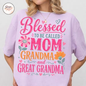 May include: A lilac t-shirt featuring the text "Blessed to be called MOM GRANDMA and GREAT GRANDMA" in pink, orange, and green. The design includes floral and heart accents.