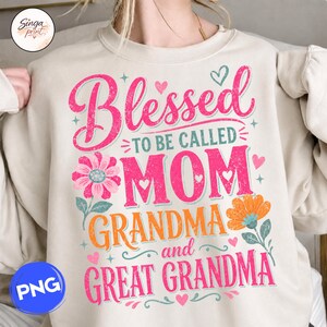 May include: A beige sweatshirt featuring the text "Blessed to be called Mom Grandma and Great Grandma" in pink and orange. The design includes floral and heart motifs, ideal for a gift.
