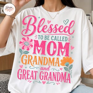 May include: White t-shirt featuring the text "Blessed to be called Mom, Grandma, and Great Grandma" in pink and orange. The design includes floral and heart motifs, ideal for celebrating mothers.
