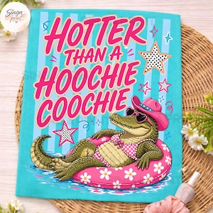May include: A turquoise t-shirt with the text "Hotter Than a Hoochie Coochie" in pink. The shirt features an alligator wearing sunglasses, a pink cowboy hat, and a gingham bikini, floating on a pink inner tube with white flowers.