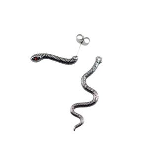 K&ouml;nnte beinhalten: Ein Paar silberfarbene Ohrstecker in Schlangenform mit texturiertem Schuppenmuster und einem kleinen roten Stein im Auge des Schlangenkopfes. Die Ohrringe bestehen aus einem Steckerverschluss und einem langen, gewundenen Schlangenk&ouml;rper aus Metall.
