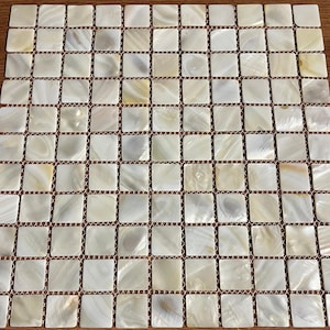 以下が含まれることがあります： 多数の小さな正方形のタイルで構成された正方形のモザイクタイルシート。各タイルは、微妙なバリエーションのある真珠光沢のあるオフホワイト色をしています。タイルはグリッドパターンに配置されており、視覚的に魅力的な表面を作り出しています。