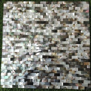 以下が含まれることがあります： 小さな長方形のピースで構成された正方形のモザイクタイル。 タイルは真珠のような光沢があり、白とグレーから黒と茶色まで色があります。 配置は、インテリアデザインに適した、テクスチャード加工されたレンガのようなパターンを作成します。