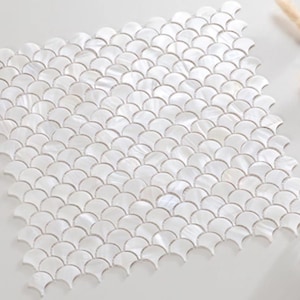 以下が含まれることがあります： 白く虹色の扇形のモザイクタイル。タイルは格子状に配置され、テクスチャのある表面を作り出しています。モザイクは、バック スプラッシュ、バスルームの壁、または装飾的なアクセントに適しています。