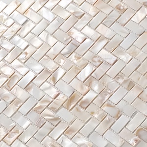Puede incluir: Primer plano de un patrón de mosaico. Azulejos rectangulares dispuestos en espiga. Los azulejos son principalmente blancos con sutiles variaciones beige y brillo nacarado.