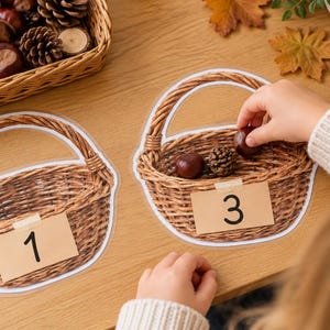 Op de afbeelding: Twee gelamineerde papieren uitsparingen van gevlochten manden, elk voorzien van een rechthoekig beige label met een zwart cijfer. De ene mand heeft het nummer 1 en de andere het nummer 3, met daarin twee bruine kastanjes en een kleine dennenappel.
