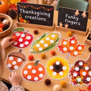 May include: A set of autumn-themed activity cards featuring illustrations of an apple, corn, a maple leaf, an acorn, a pumpkin, a sunflower, and a cornucopia, each with white circular spaces for pom-poms, alongside two signs labeled Thanksgiving creations and Funky fingers.