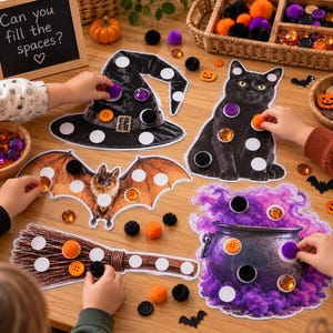 May include: A Halloween-themed activity set featuring cardboard cutouts of a witch hat, a black cat, a bat, a broom, and a cauldron with purple smoke. The cutouts have white circles for placing orange, black, and purple pom-poms or buttons.