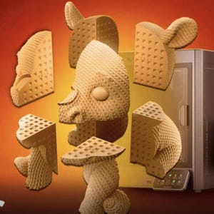 May include: A light brown sculpture of a face and body, broken into several pieces, with a 3D printer in the background. The sculpture has a waffle-like pattern on some surfaces and a smooth, rounded shape for the face.