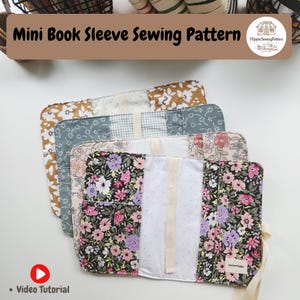 May include: Four fabric book sleeves with floral and patterned designs are stacked. The sleeves are in shades of brown, blue, pink, and black. The text "Mini Book Sleeve Sewing Pattern" is at the top, with a video tutorial icon at the bottom.