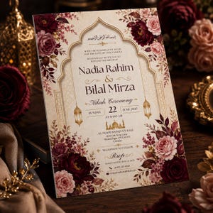 May include: A rectangular wedding invitation card featuring a cream background with an ornate gold arch frame, decorated with deep burgundy and soft pink roses. The text includes the names Nadia Rahim and Bilal Mirza for a Nikah ceremony.
