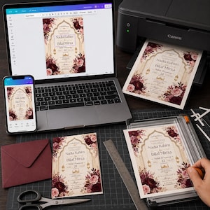 May include: A wedding invitation design featuring deep burgundy and blush floral arrangements, gold archway accents, and the text Nadia Rahim & Bilal Mirza. The invitation is displayed on a laptop screen, a smartphone, a printer, and a paper cutter.