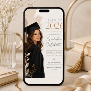May include: A smartphone displays a graduation announcement. The design features a woman in a graduation gown and cap. Text includes "Class of 2026" and "Graduation Celebration". The background is beige with floral accents.