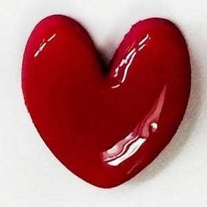 May include: A three-dimensional heart-shaped object with a smooth, glossy, deep red finish. The surface reflects light, creating bright white highlights that emphasize the rounded, puffed contours of the heart shape.