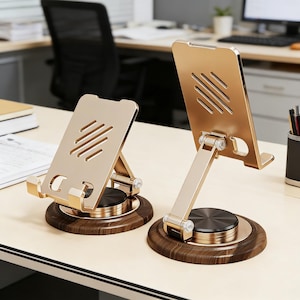 May include: Two gold-coloured phone stands with a wood-grain base are displayed on a light-coloured desk. Each stand has a rectangular back with diagonal cutouts and an adjustable arm. The base is round and has a dark brown wood-grain finish.