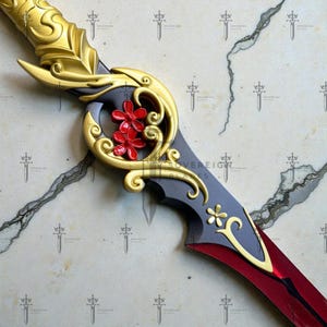 May include: A decorative sword with a gold hilt and accents, featuring red floral embellishments. The blade is a deep red color, transitioning to a darker gray near the hilt. The design includes ornate gold detailing.