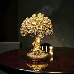 May include: A gold-coloured incense burner in the shape of a tree, adorned with intricate coin and ingot details. The tree rests on a decorative base and emits a wisp of smoke. It is placed on a dark, reflective surface, creating a mirrored effect.
