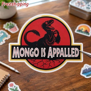 May include: A circular sticker featuring a black silhouette of a feathered dinosaur inside a red circle with a yellow border. Below the circle, a black rectangular banner contains the white text "MONGO IS APPALLED" in a bold, serif font.