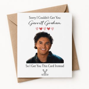 May include: A white greeting card with the text "Sorry I Couldn't Get You Garrett Graham" and "So I Got You This Card Instead." The card features a photo of a smiling man and hockey sticks.