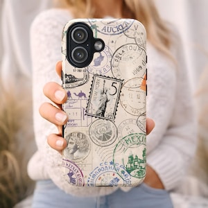 May include: A phone case featuring a collage of vintage travel stamps in various colors, including green, purple, and red. The stamps showcase destinations like New York, Chicago, and Italy. The case is held in a person's hand.