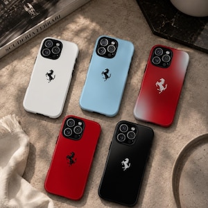 Può includere: Cinque cover per smartphone con il logo di un cavallino rampante. La collezione include una cover bianca, una azzurra, una con sfumatura dal rosso al bianco, una rossa tinta unita e una nera. Ogni cover ha un ritaglio per la tripla fotocamera.