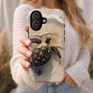 May include: A phone case featuring a detailed image of a sea turtle swimming in shallow water. The turtle has a brown and tan shell with dark flippers. The background depicts a sandy beach with gentle waves.