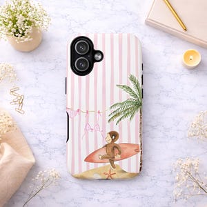 May include: A phone case with a pink and white striped background. The case features a cartoon illustration of a monkey carrying a surfboard on a beach with a palm tree. Pink bikinis hang on a clothesline.