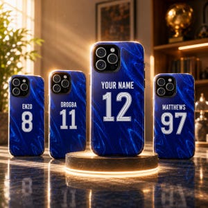 May include: Four blue smartphone cases with a marbled pattern, each featuring white text and numbers. The cases display the names ENZO, DROGBA, YOUR NAME, and MATTHEWS, paired with the numbers 8, 11, 12, and 97 respectively, in a sports jersey style.