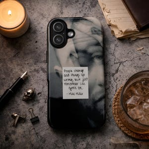 May include: Black phone case featuring a grayscale image of a person's face and a quote: "People change and things go wrong, but just remember life goes on. - Mac Miller." The case has a black border and a dual-lens camera cutout.