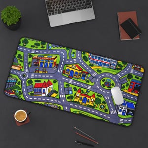 Könnte beinhalten: Rechteckiges Mauspad mit farbenfrohem Stadtplan-Design, einschließlich Straßen, Gebäuden und Grünflächen. Zu den Gebäuden gehören eine Feuerwache, ein Krankenhaus und eine Schule. Eine weiße Computermaus liegt darauf.